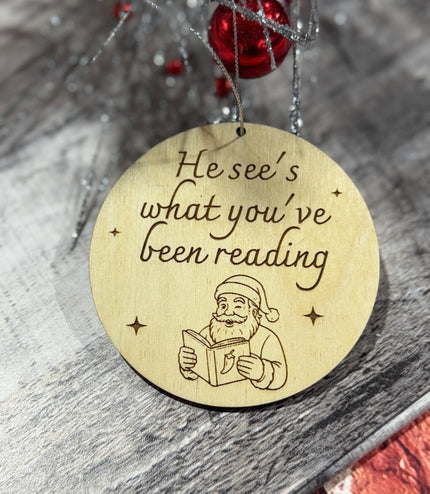 He see’s what you’ve been reading ornament, spicy book, spicy book ornament, funny reading ornament, book lover, Santa reading,