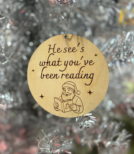 He see’s what you’ve been reading ornament, spicy book, spicy book ornament, funny reading ornament, book lover, Santa reading,